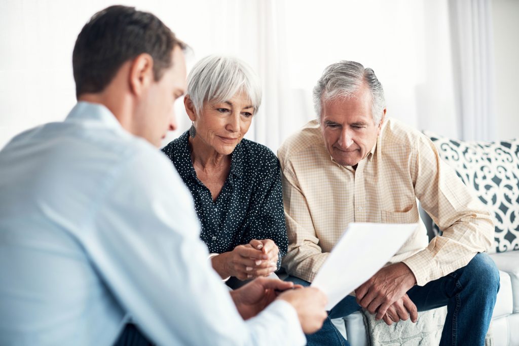 Older couple reviewing assisted living cost documents with advisor at home